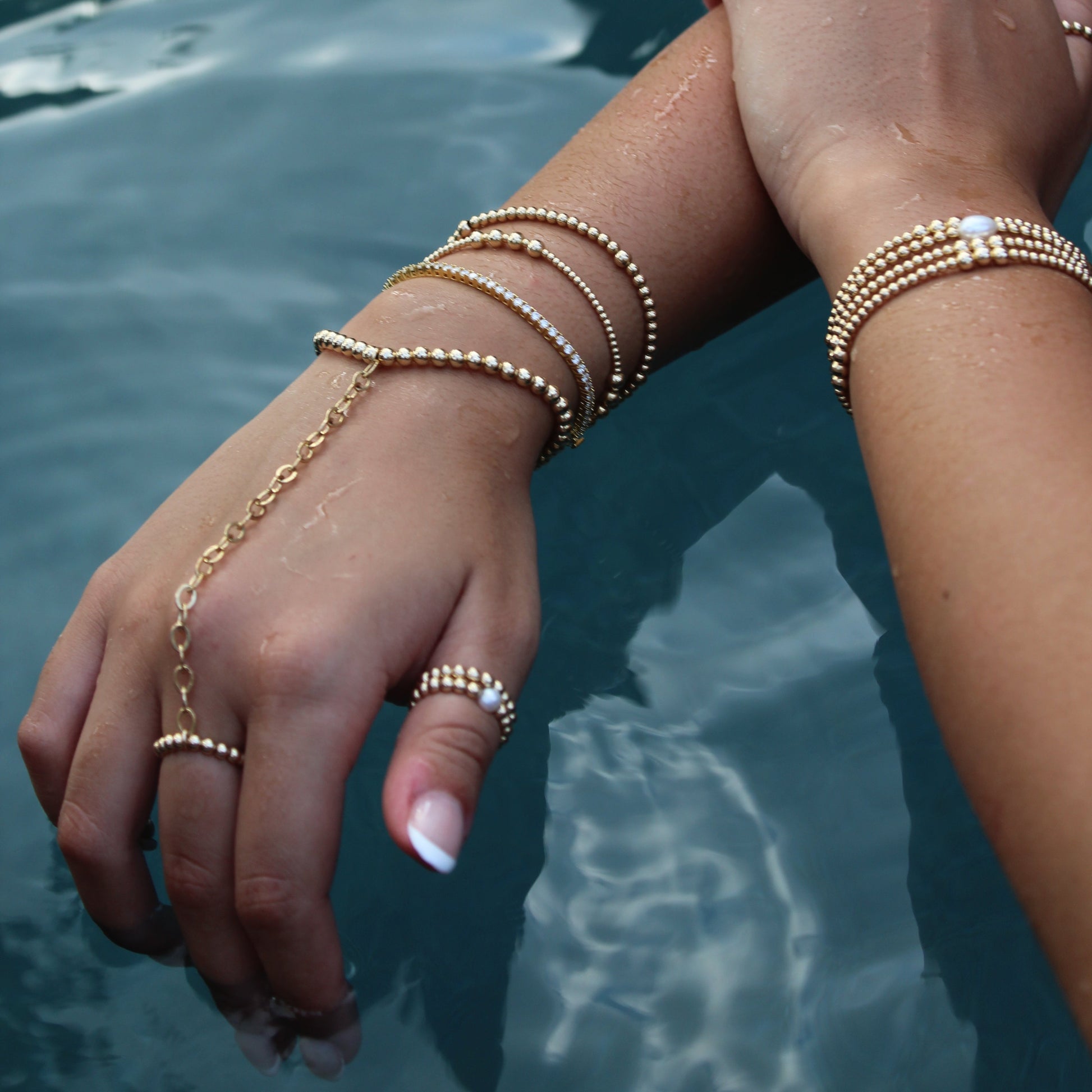 Close-up of hands with gold jewelry against a blurred natural background